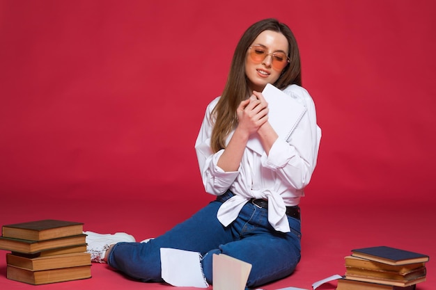 Foto de una estudiante decepcionada usando libros de ejercicios mientras se sienta en el suelo