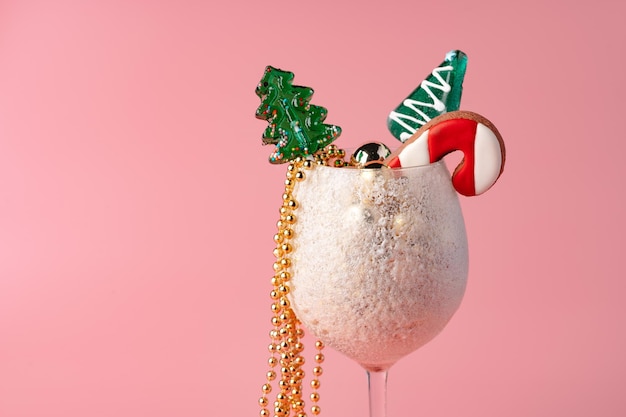 Foto de estudio de adornos navideños en un vaso contra fondo de color rosa