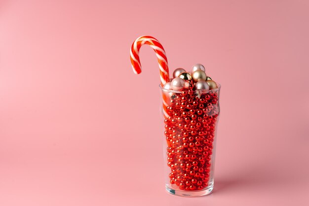 Foto de estudio de adornos navideños en un vaso contra fondo de color rosa