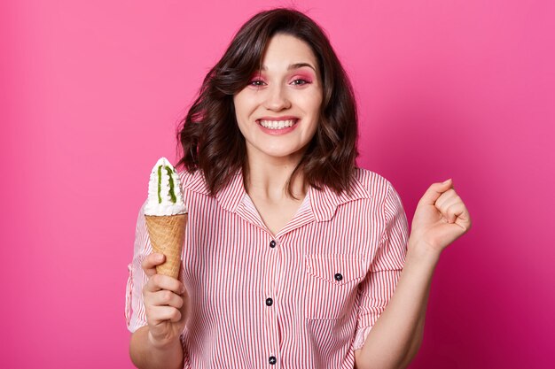 Foto de estudio de alegre mujer de pelo oscura tiene helado