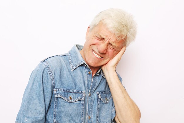 Foto de estudio de un anciano infeliz presionando la mejilla tratando de calmar el dolor de muelas