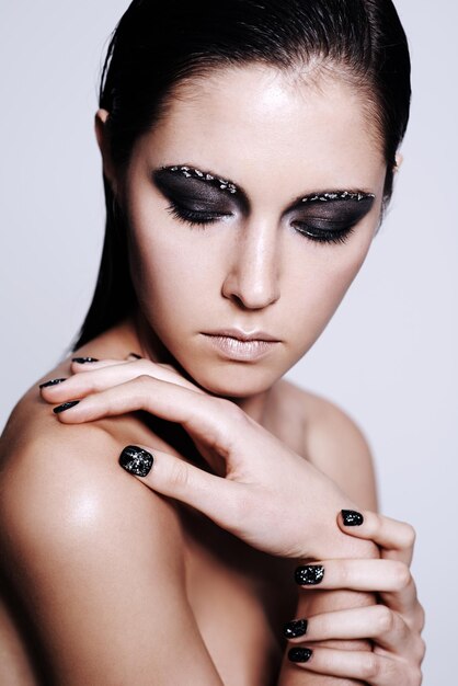 Foto de estudio de belleza intensa de una hermosa mujer joven con maquillaje de color metálico y esmalte de uñas