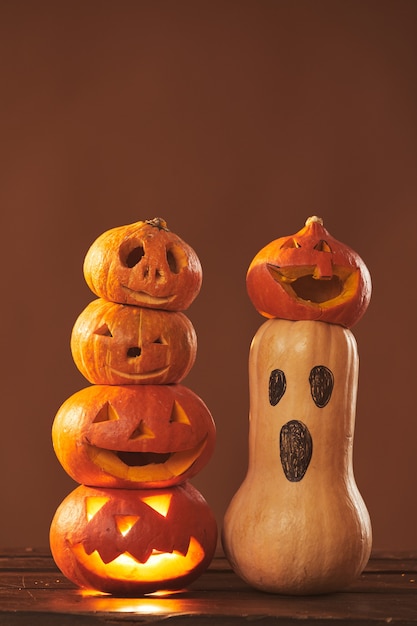Foto de estudio de composición de bodegón de calabazas maduras talladas y pintadas para decoración de fiesta de Halloween, superficie marrón