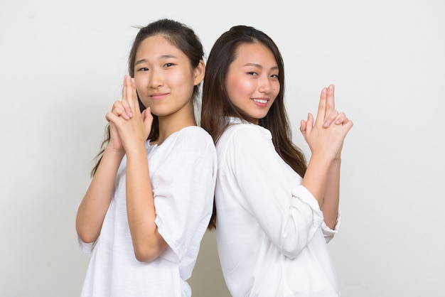 Foto de estudio de dos jóvenes hermosas mujeres coreanas como amigos juntos contra el fondo blanco.