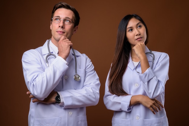 Foto de estudio de dos jóvenes médicos juntos contra backgrou marrón