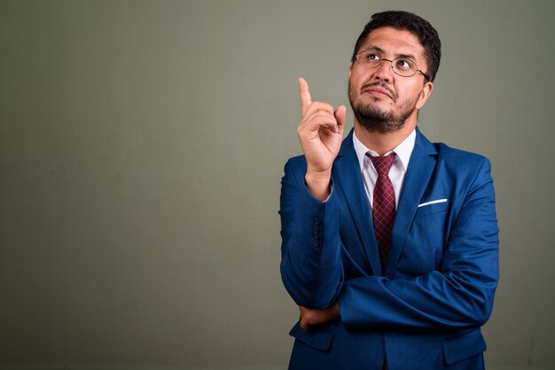 Foto de estudio del empresario barbudo vistiendo traje contra color