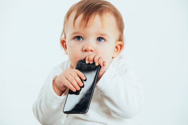 Foto de estudio con el fondo blanco de la cara de un bebé con un móvil en las manos