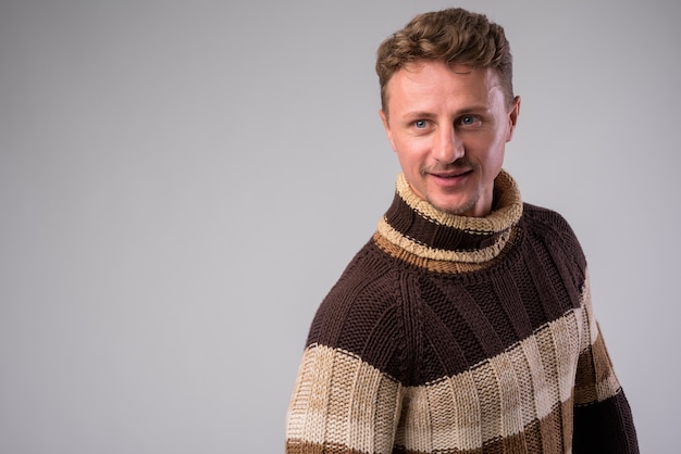 Foto de estudio de guapo hombre barbudo vestido con suéter de cuello alto listo para el invierno