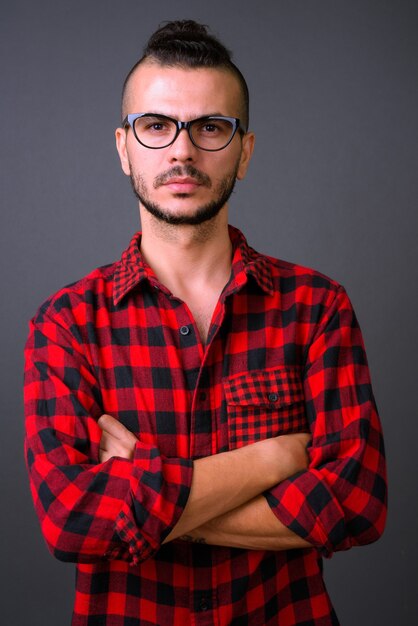 Foto de estudio de guapo turco hombre con anteojos contra un fondo gris