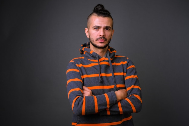 Foto de estudio de guapo turco hombre vestido con capucha contra un fondo gris