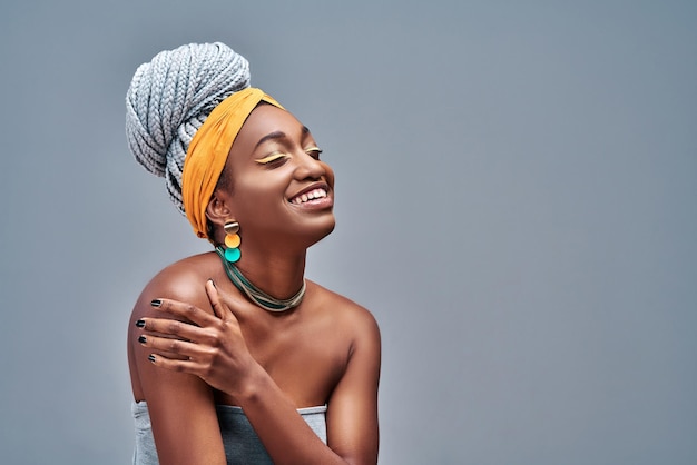 Foto de estudio de una hermosa y encantadora joven afro que ha complacido la feliz expresión facial cerrando los ojos