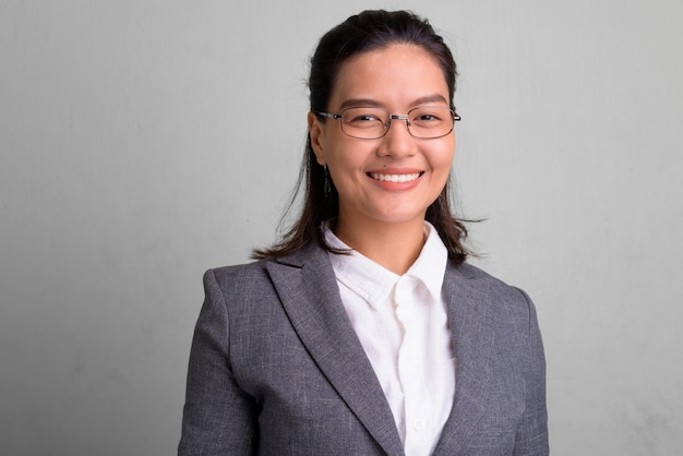 Foto de estudio de hermosa joven empresaria asiática con anteojos contra un blanco