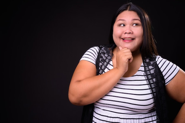 Foto de estudio de hermosa mujer asiática con sobrepeso contra fondo negro