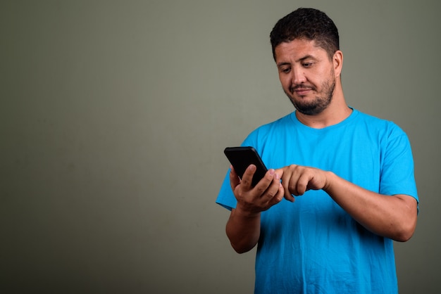 Foto de estudio de hombre barbudo vestido con camisa azul contra color