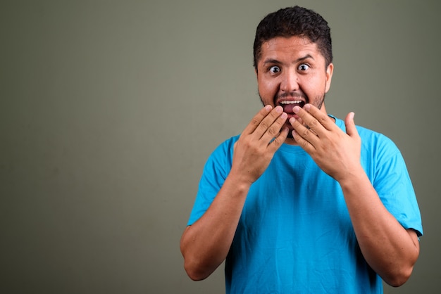 Foto de estudio de hombre barbudo vestido con camisa azul contra color