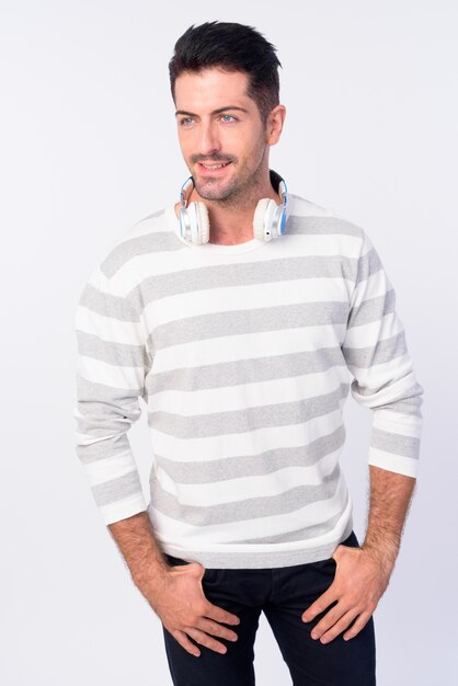 Foto de estudio de hombre guapo con barba con auriculares alrededor del cuello aislado contra el fondo blanco.