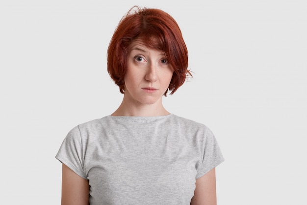 Foto foto de estudio de infeliz mujer pelirroja vestida con camiseta gris casual