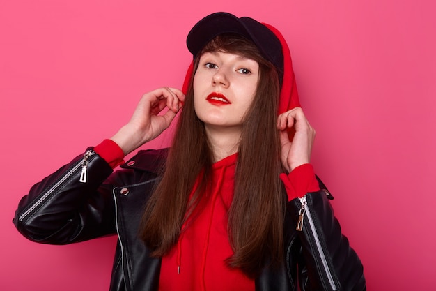 Foto de estudio de la joven adolescente bonita con sudadera roja y chaqueta de cuero