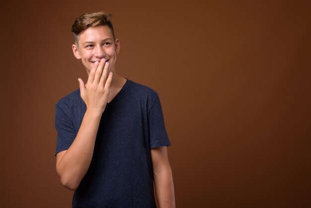 Foto de estudio de joven adolescente guapo contra backgrou marrón