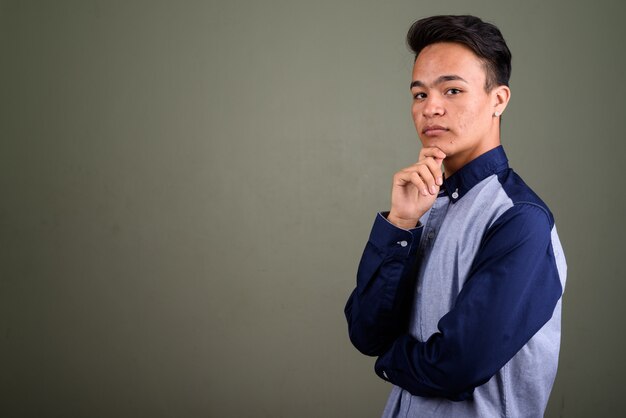 Foto de estudio de joven adolescente mirando inteligente contra color