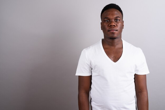 Foto de estudio de joven africano con camisa blanca contra el fondo blanco.