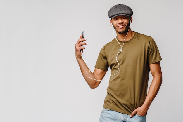 Foto de estudio joven afroamericano escuchando música con auriculares