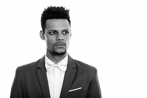 Foto de estudio de joven apuesto hombre de negocios africano con barba en traje aislado sobre fondo blanco en blanco y negro