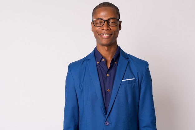 Foto de estudio de joven apuesto hombre de negocios africano calvo en traje con anteojos contra el fondo blanco.