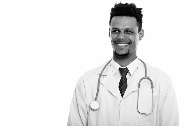 Foto de estudio de joven apuesto médico africano barbudo aislado sobre fondo blanco en blanco y negro