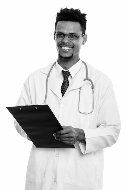 Foto de estudio de joven apuesto médico africano barbudo aislado sobre fondo blanco en blanco y negro