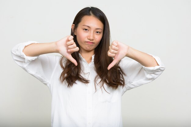 Foto de estudio de la joven y bella empresaria coreana contra el fondo blanco.