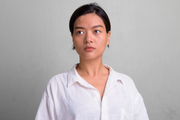 Foto de estudio de joven bella mujer con cabello atado contra un blanco