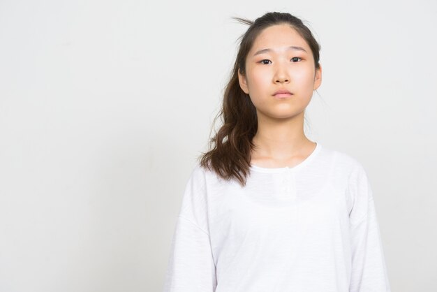 Foto de estudio de la joven y bella mujer coreana contra el fondo blanco.