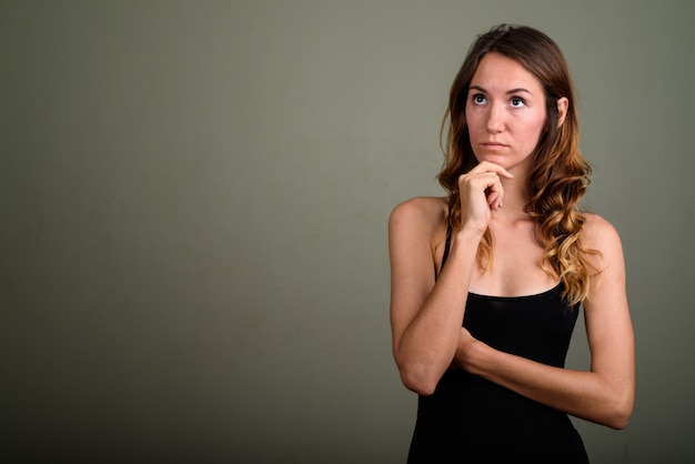 Foto de estudio de joven bella mujer vistiendo top sin mangas con fondo de color