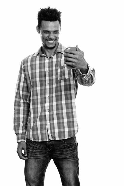 Foto de estudio de joven empresario africano barbudo con cabello afro aislado sobre fondo blanco en blanco y negro