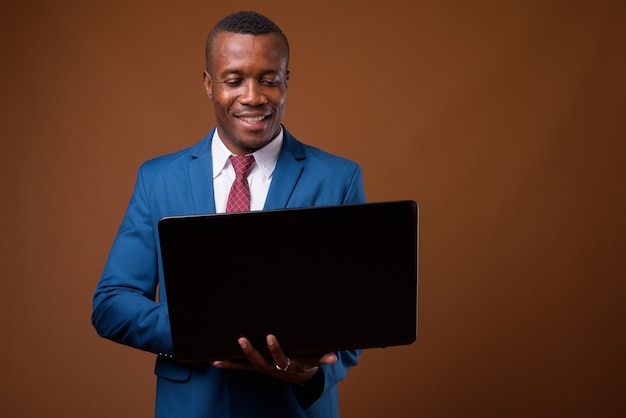 Foto de estudio del joven empresario africano contra el fondo marrón