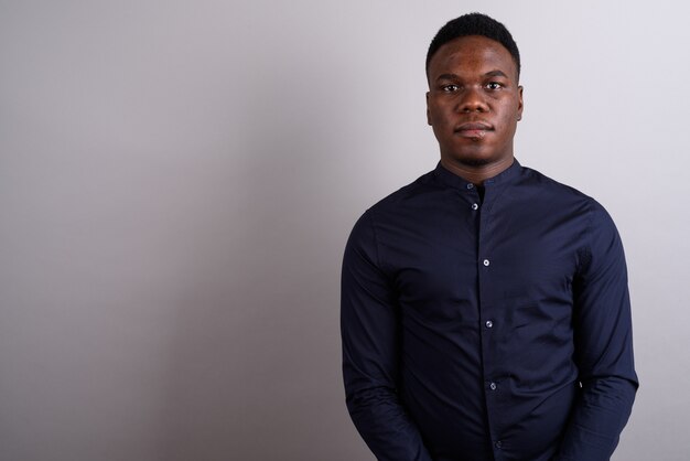 Foto de estudio del joven empresario africano vistiendo camisa azul contra el fondo blanco.