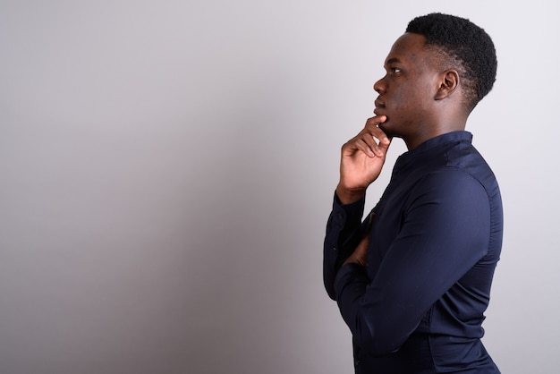 Foto de estudio del joven empresario africano vistiendo camisa azul contra el fondo blanco.