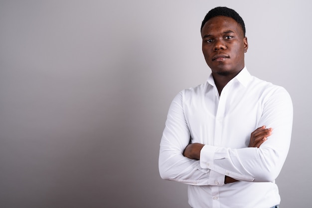 Foto de estudio del joven empresario africano vistiendo camisa blanca contra el fondo blanco.