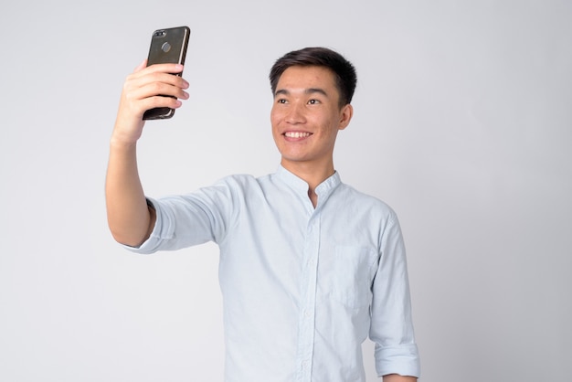 Foto de estudio de joven empresario asiático guapo contra el fondo blanco.