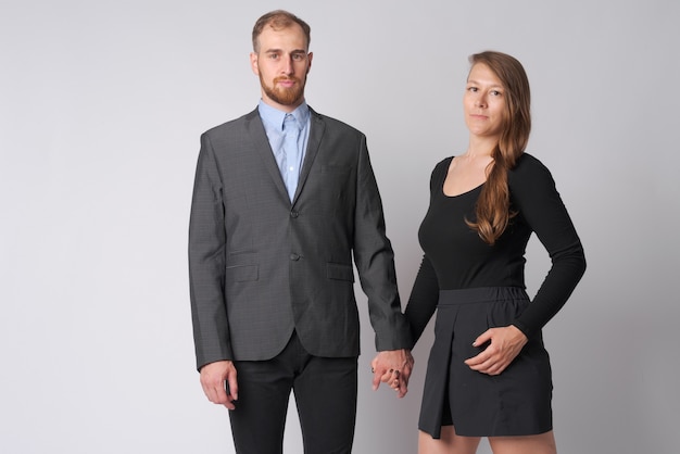 Foto de estudio de joven empresario barbudo y joven empresaria juntos contra un blanco