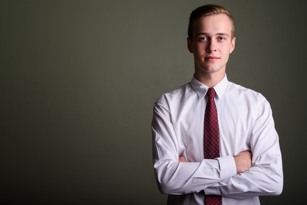 Foto de estudio de joven empresario guapo con cabello rubio contra el fondo de color