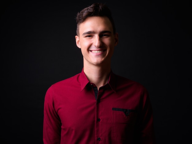 Foto de estudio de joven empresario guapo en camisa roja sobre fondo negro