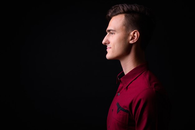 Foto de estudio de joven empresario guapo en camisa roja sobre fondo negro