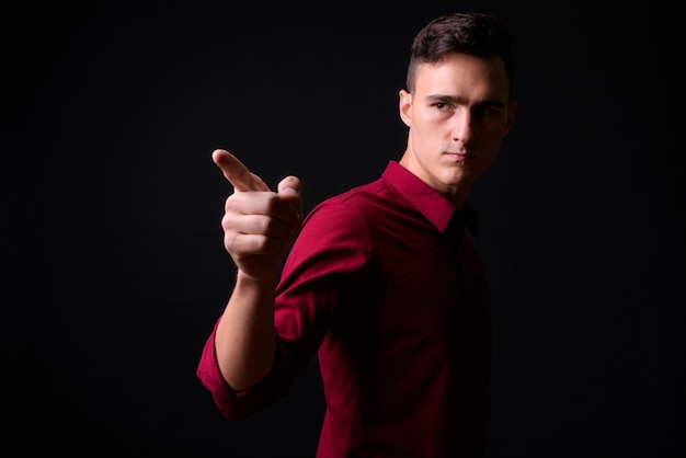 Foto de estudio de joven empresario guapo en camisa roja sobre fondo negro