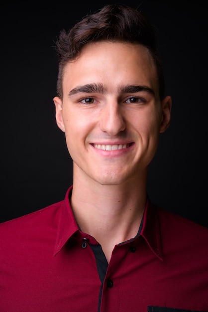 Foto foto de estudio de joven empresario guapo en camisa roja sobre fondo negro