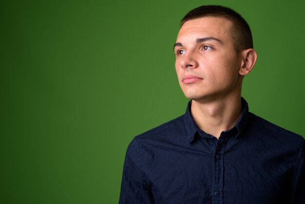 Foto de estudio de joven empresario guapo contra backgrou verde