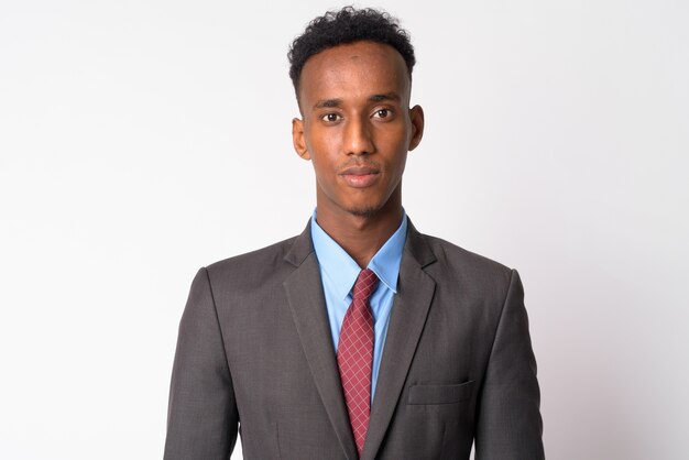 Foto de estudio de joven empresario guapo con pelo afro vistiendo traje contra un blanco