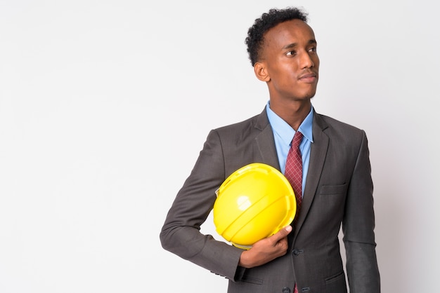 Foto de estudio de joven empresario guapo con pelo afro vistiendo traje contra un blanco