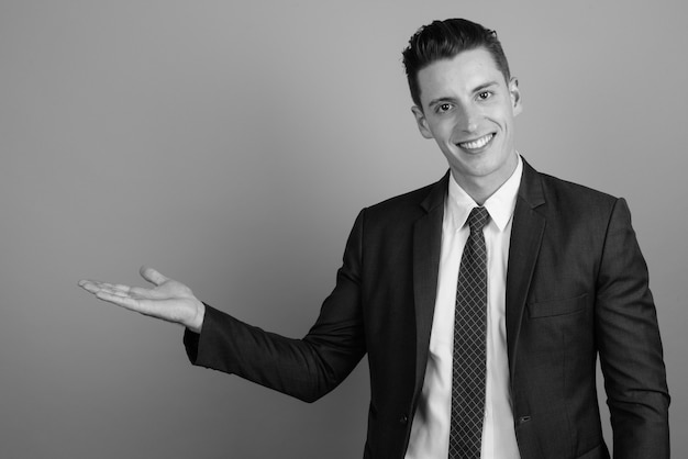 Foto de estudio de joven empresario guapo vistiendo traje contra un fondo gris en blanco y negro